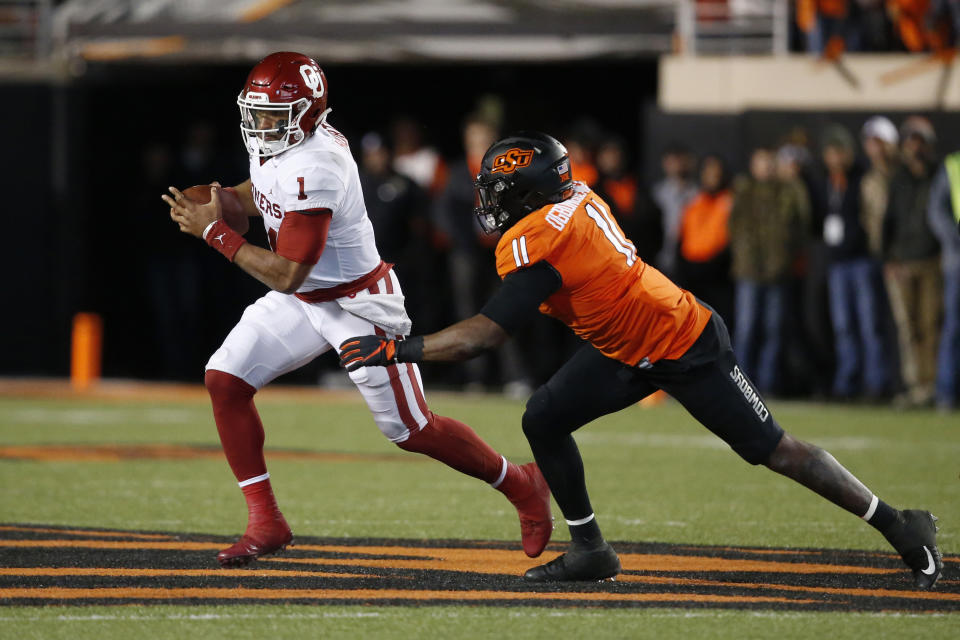 Oklahoma quarterback Jalen Hurts (1) is pursued by Oklahoma State linebacker Amen Ogbongbemiga (11) in the second half of an NCAA college football game in Stillwater, Okla., Saturday, Nov. 30, 2019. (AP Photo/Sue Ogrocki)