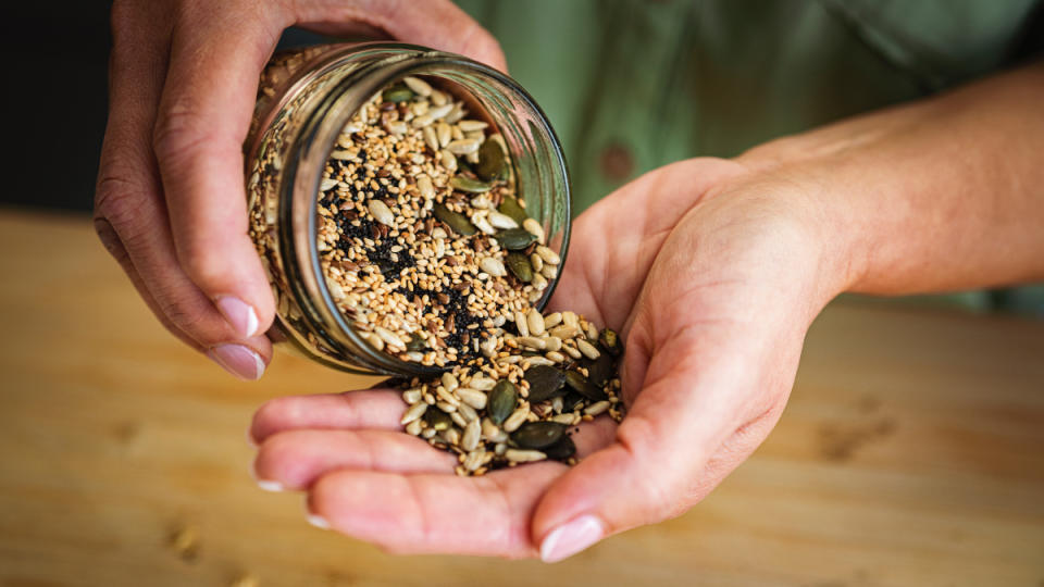 A close-up of a woman pouring seeds out of a jar into her hand