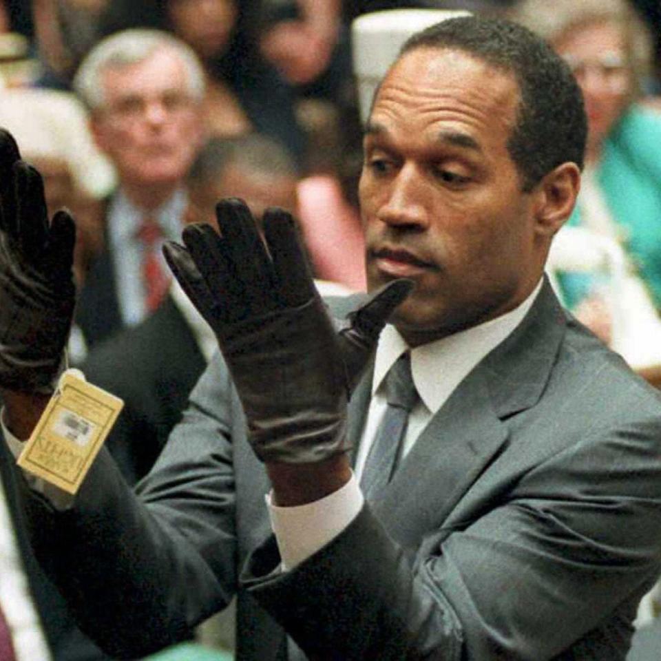 OJ Simpson looks at a new pair of Aris extra-large gloves that prosecutors had him put on during his double-murder trial in Los Angeles in 1995. - Credit: AFP
