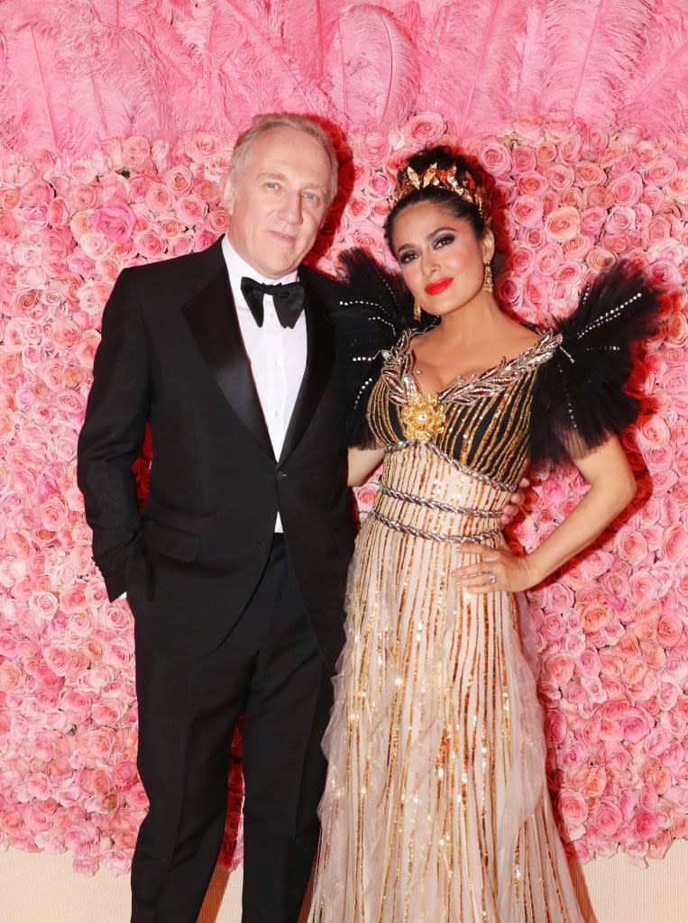 the two pose in front of a rose covered wall