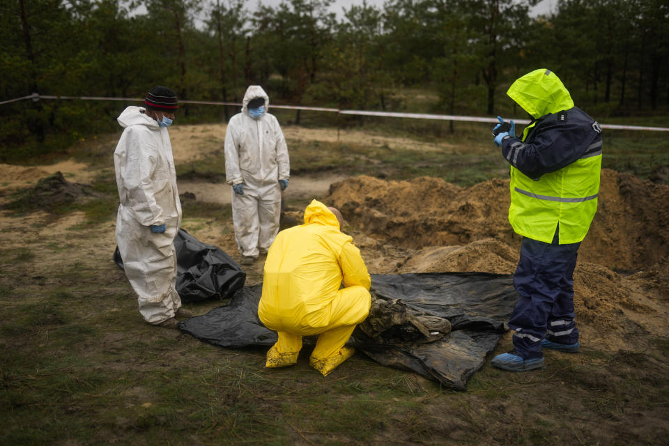 Members of a forensic team at work during an exhumation at a mass grave in Lyman, Ukraine, Tuesday, Oct. 11, 2022. (AP Photo/Francisco Seco)