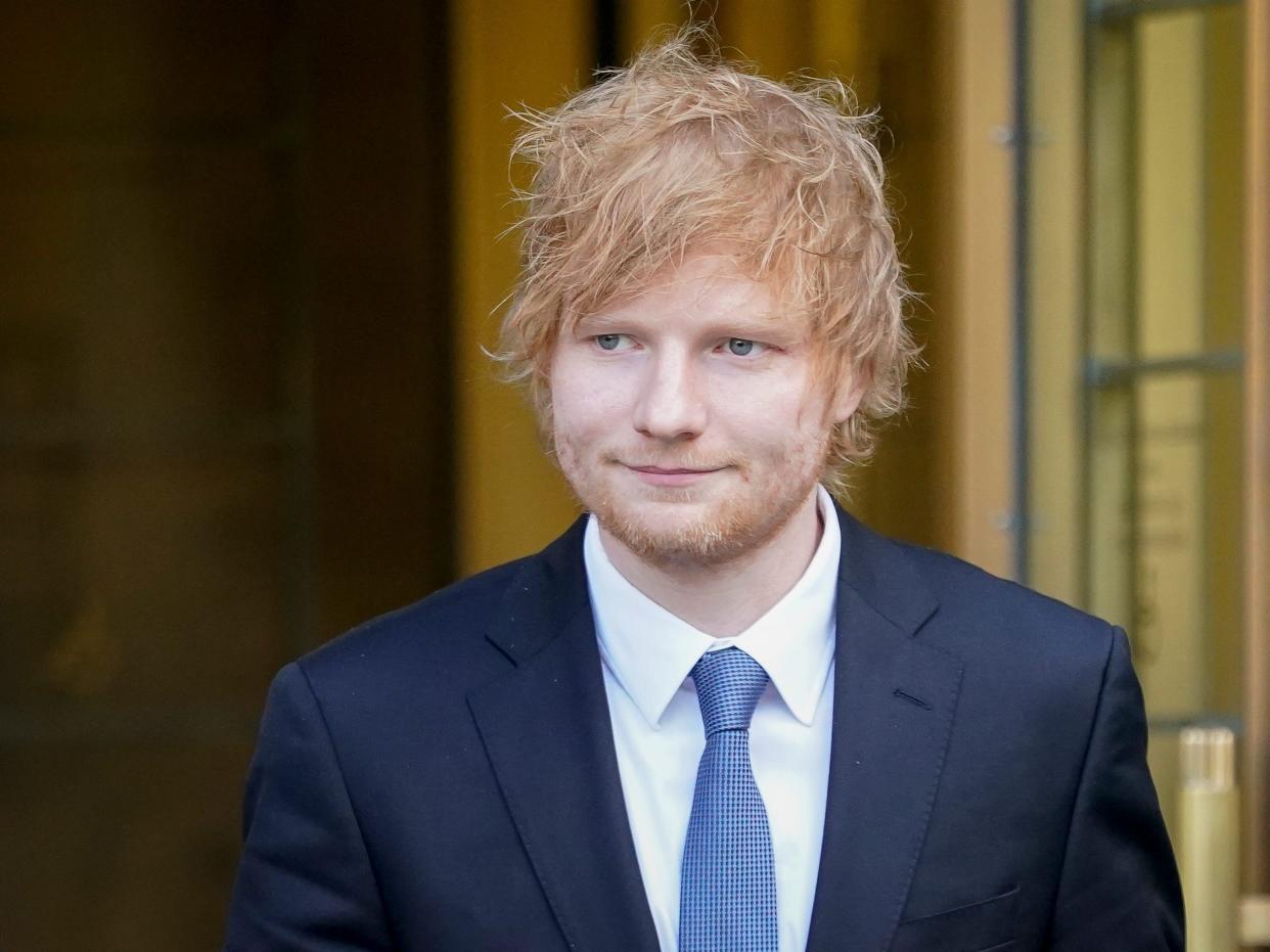 Ed Sheeran wearing a suit while standing outside the doorway in a federal court in Manhattan.