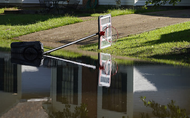 A downed basketball goal is reflected in flood waters in northeast Jackson, Miss.