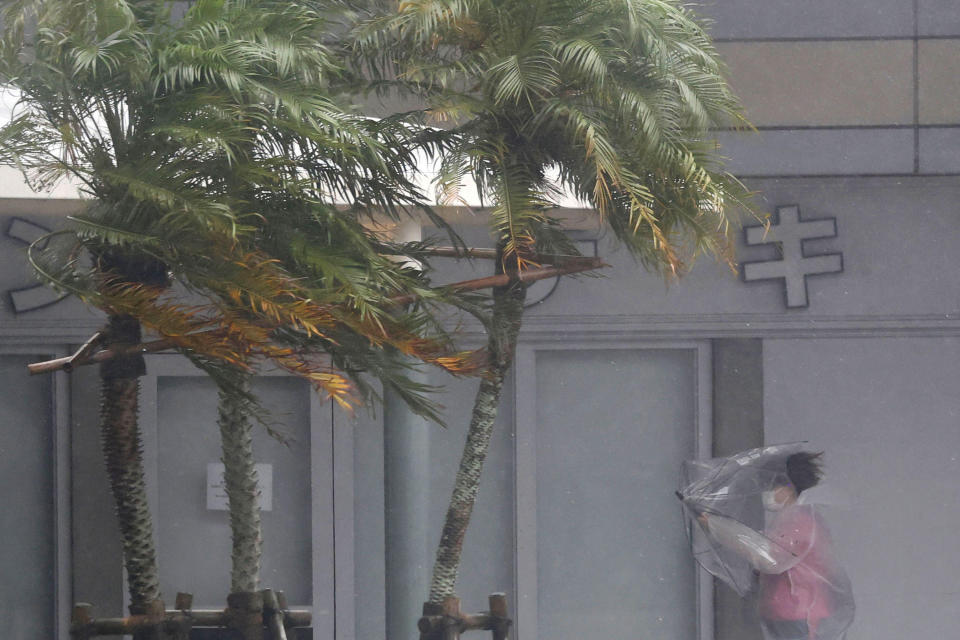 A woman makes her way through the strong wind and rain in Miyazaki, southern Japan, Sunday, Sept. 18, 2022, as a powerful typhoon pounded southern Japan. (Kyodo News via AP)