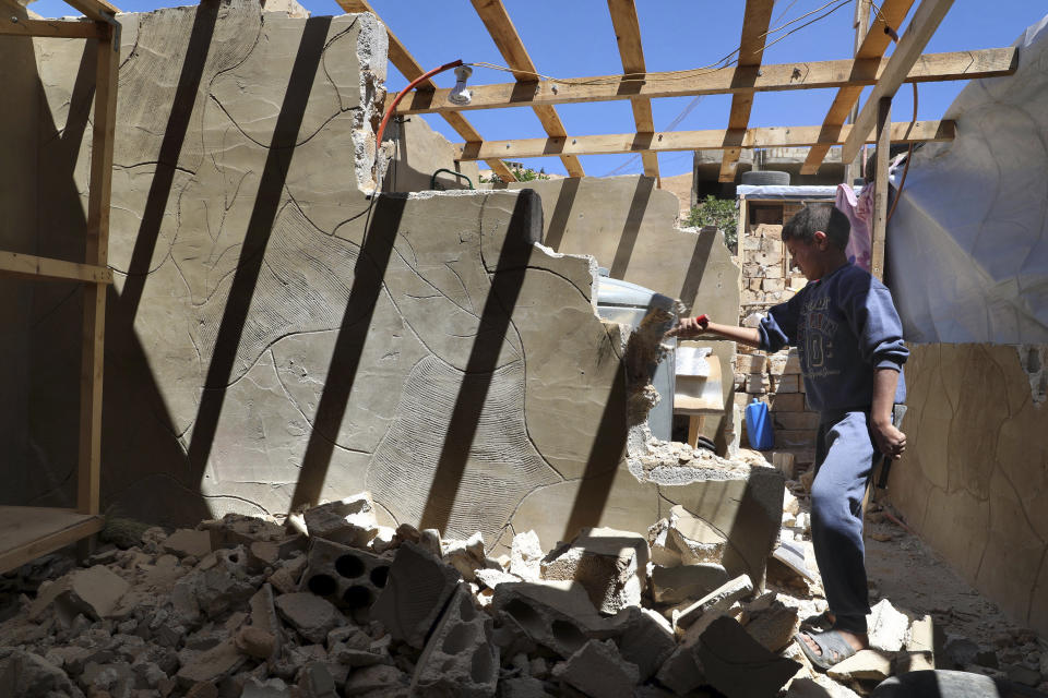 In this Sunday, June 16, 2019 photo, a Syrian refugee boy demolishes a concrete wall built inside his family tent in a refugee camp in the eastern Lebanese border town of Arsal, Lebanon. Authorities in Lebanon are waging their most aggressive campaign yet against Syrian refugees, making heated calls for them to go back to their country and taking action to ensure they can’t put down roots. They are shutting down shops where Syrians work without permits and ordering the demolition of anything in their squalid camps that could be a permanent home. (AP Photo/Bilal Hussein)