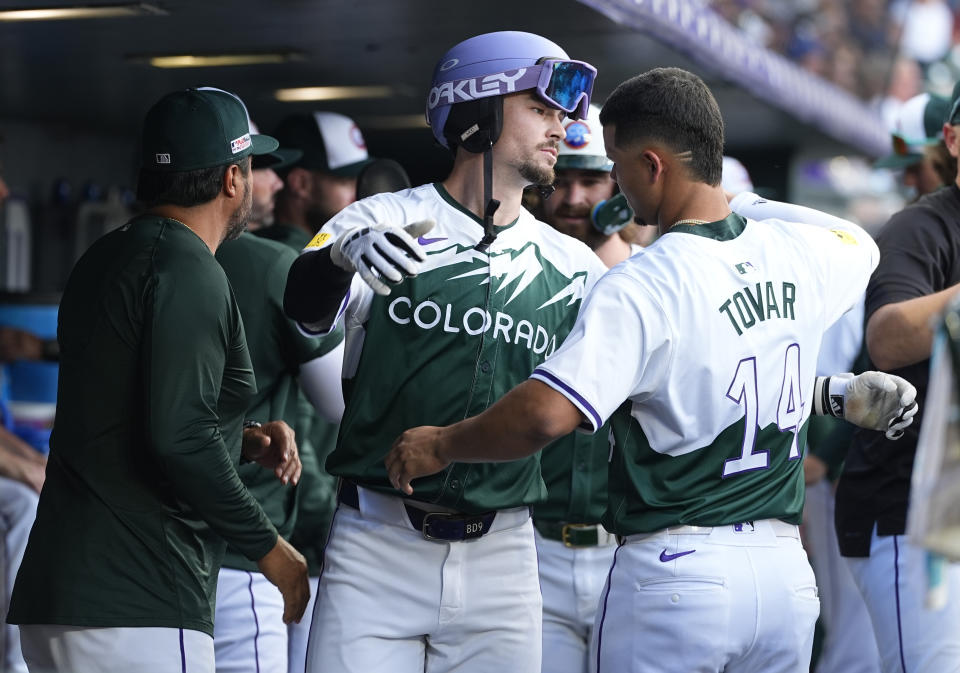 Colorado Rockies' Brenton Doyle, center, hugs Ezequiel Tovar as Vinny Castilla, special assistant to the general manager, looks on as Doyle returns to the dugout after hitting a teo-run home run off Kansas City Royals starting pitcher Seth Lugo in the second inning of a baseball game Saturday, July 6, 2024, in Denver. (AP Photo/David Zalubowski)