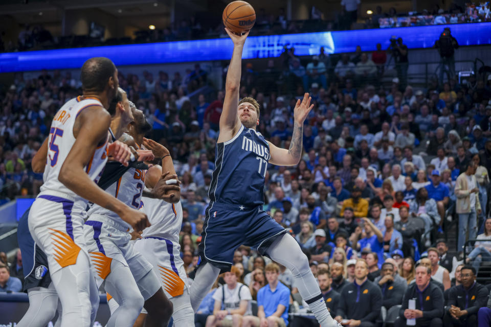 Dallas Mavericks guard Luka Doncic (77) pulls up to shoot while being defended by a group of Phoenix Suns players during the first half of an NBA basketball game, Sunday, March 5, 2023, in Dallas. (AP Photo/Gareth Patterson)