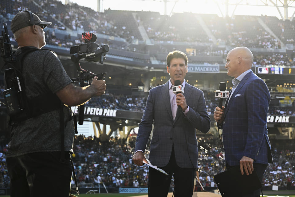 MLB broadcasters Mike Pomeranz, back left, and Mark Sweeney speak before a baseball game between the Los Angeles Angels and the San Diego Padres on Monday, July 3, 2023, in San Diego. (AP Photo/Denis Poroy)