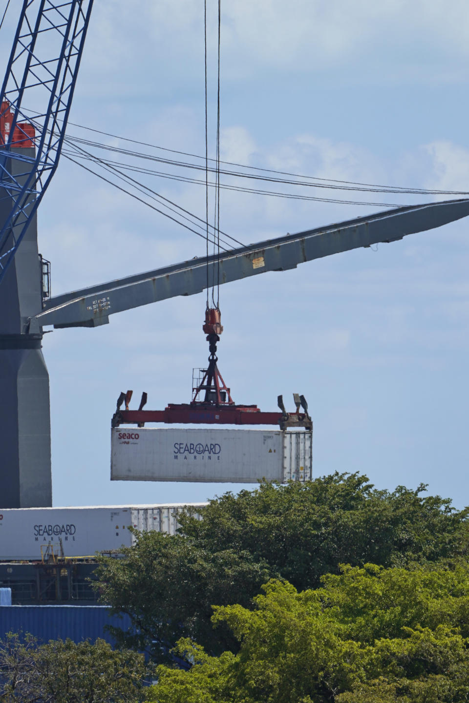 In this April 9, 2021 photo a cargo container is unloaded from a ship docked at PortMiami n Miami. Importers are contending with a perfect storm of supply trouble — rising prices, overwhelmed ports, a shortage of ships, trains, trucks — that is expected to last into 2022. (AP Photo/Wilfredo Lee)