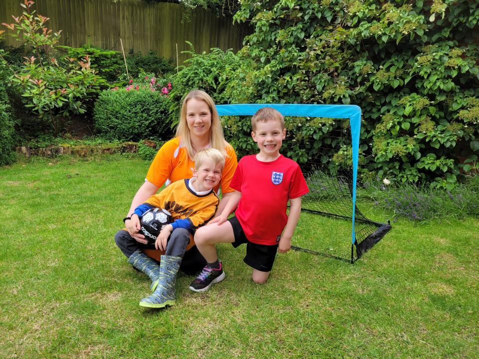 Woman holding a boy, with another kneeling next to them and smiling 