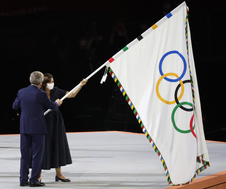 TOKYO, JAPAN - AUGUST 8, 2021: IOC president Thomas Bach (front) hands the Olympic flag to Paris Mayor Anne Hidalgo during the closing ceremony of the 2020 Summer Olympic Games at the Japan National Stadium (a.k.a the Olympic Stadium). The Olympic Games were held amid the COVID-19 pandemic. The closing ceremony features live and pre-recorded elements. Paris is to host the next summer Olympic games in 2024. Stanislav Krasilnikov/TASS (Photo by Stanislav Krasilnikov\TASS via Getty Images)