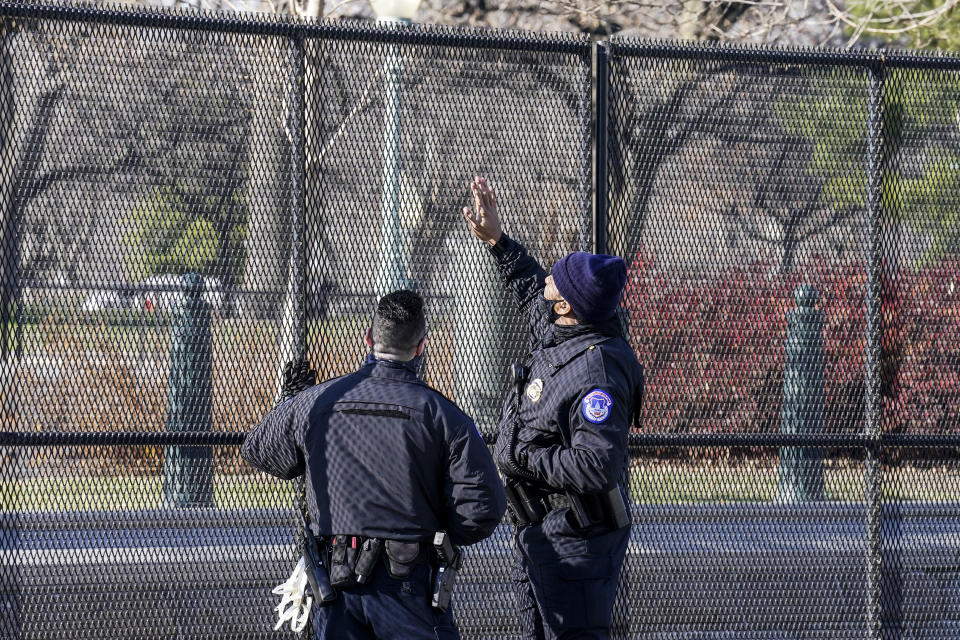 Capitol police officers look at fencing that was installed around the exterior of the Capitol grounds, Thursday, Jan. 7, 2021 in Washington. The House and Senate certified the Democrat's electoral college win early Thursday after a violent throng of pro-Trump rioters spent hours Wednesday running rampant through the Capitol. A woman was fatally shot, windows were bashed and the mob forced shaken lawmakers and aides to flee the building, shielded by Capitol Police. (AP Photo/John Minchillo)