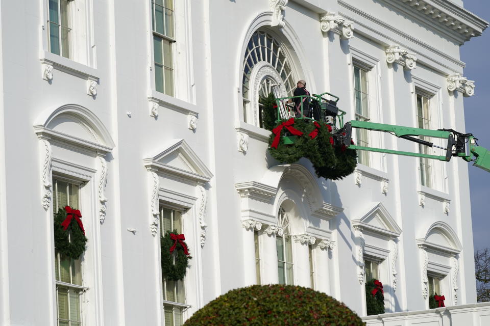 A worker hangs holiday wreaths on the White House on Saturday, Nov. 21, 2020, in Washington. (AP Photo/Jacquelyn Martin)