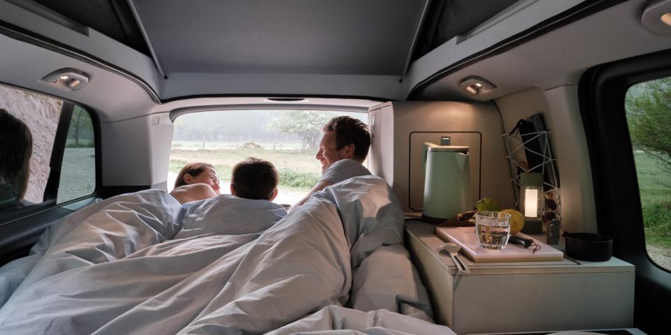 A bed inside the camper van with people near the rear.