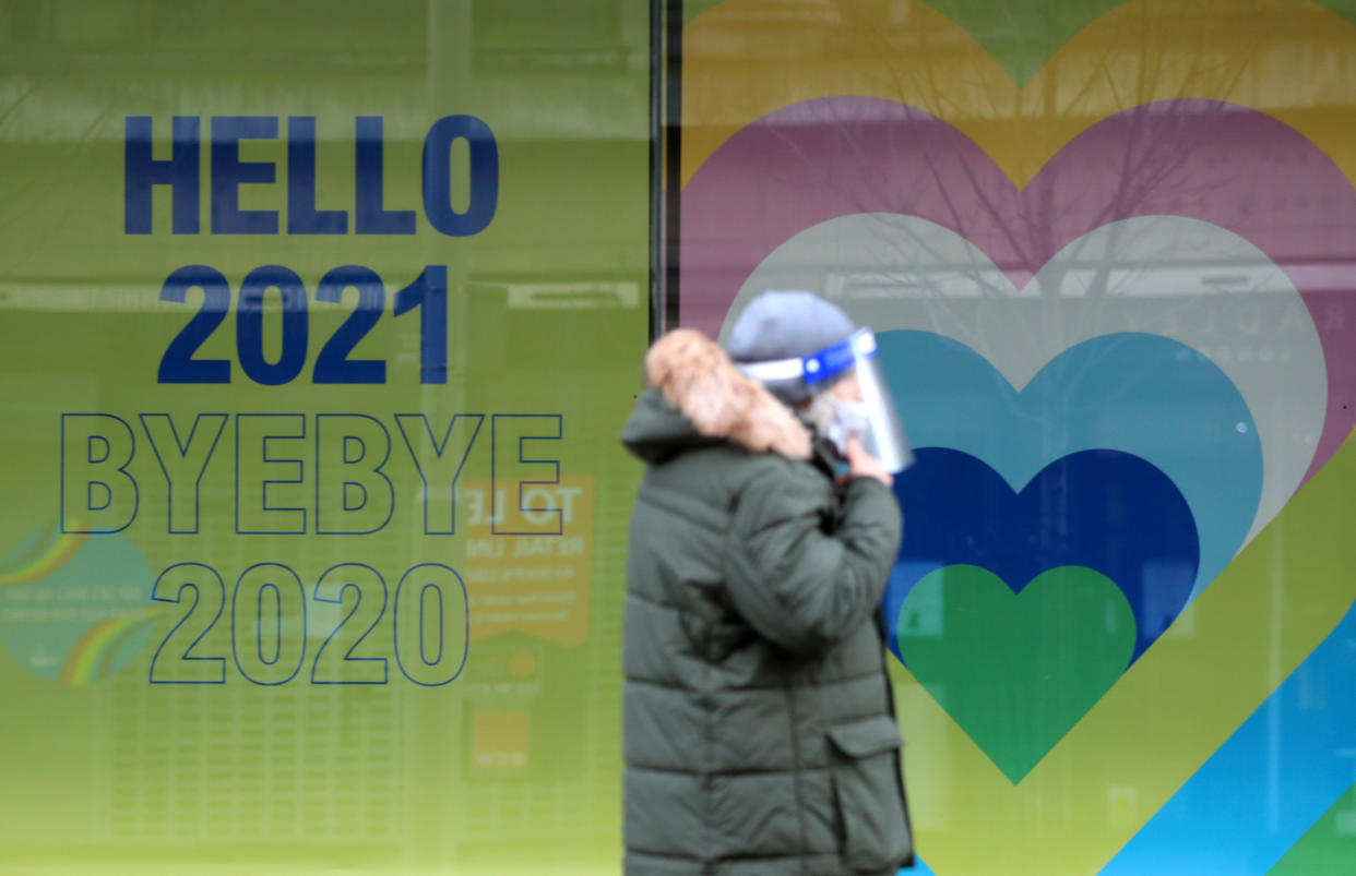 A shopper in Nottingham City Centre walks past a New Year sign. More than three quarters of England's population is being ordered to stay at home to stop the spread of coronavirus.