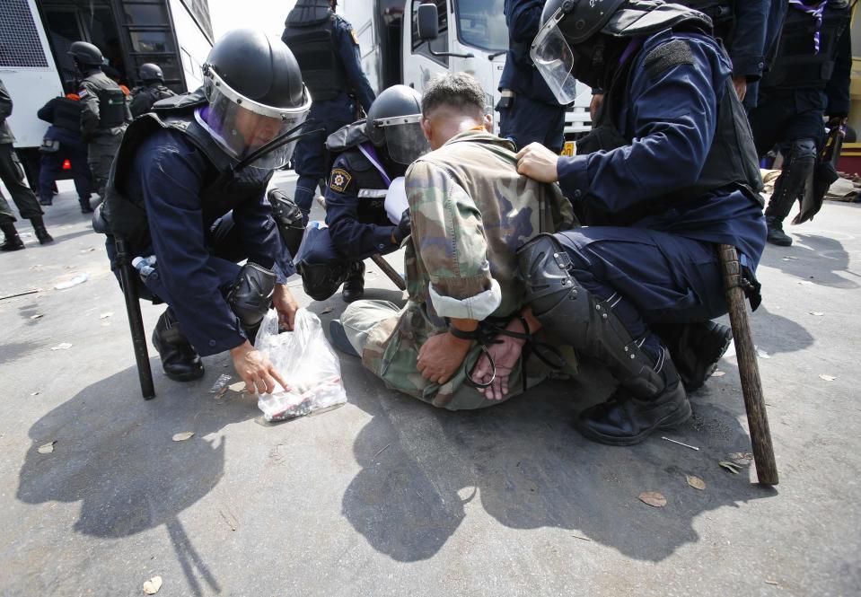 Thai police officers detain an anti-government protester near Government House in Bangkok