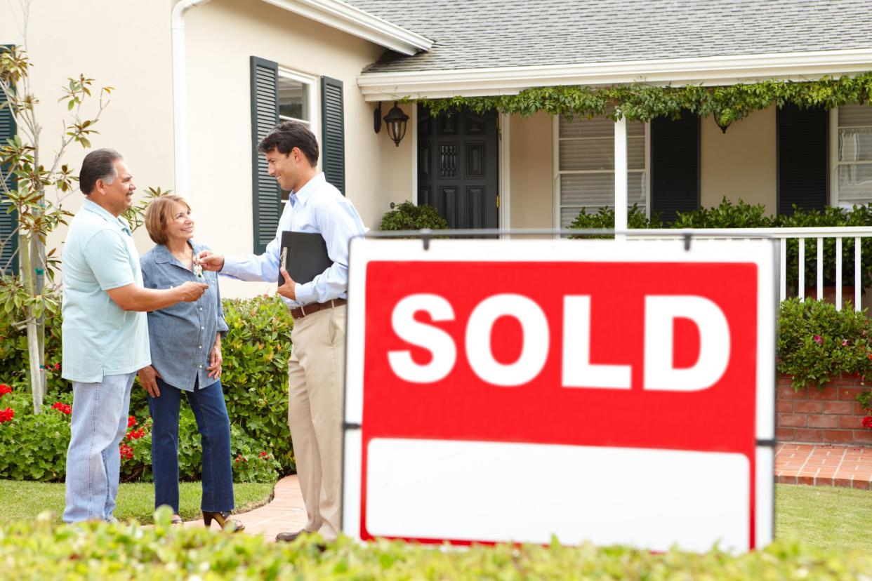 Senior Hispanic couple buying new home talking to estate agent