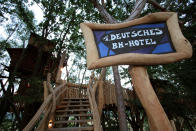 A welcome sign is displayed at the entrance to Germany's first tree house hotel in eastern village of Zentendorf near the Polish border July 15, 2005. The Tree House hotel in Saxony, offers five wooden rooms suspended in branches 30-feet above the ground, connected by narrow walkways and built into the branches of black locust trees. The rooms come with small balconies, electric lights and shared toilets cost around 160 euros a night. REUTERS/Pawel Kopczynski