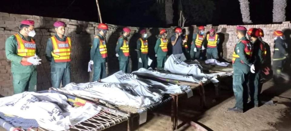 Rescue workers gather near the bodies of the victims in Muzaffargarh, Pakistan (REUTERS)