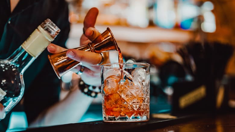 bartender pouring spirits into glass