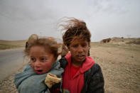 A displaced Iraqi girl, who fled from home, carries her sister during a battle with Islamic State militants on the outskirts of the Badush, Iraq, March 13, 2017. REUTERS/Stringer