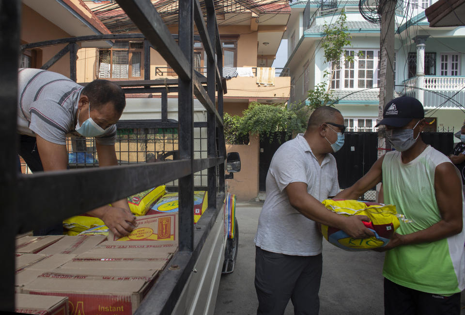 Trekking guide Ang Phurba Sherpa, left, distributes ration to fellow guides, in Kathmandu, Nepal, Monday, June 7, 2021. Most Sherpa guides in Nepal famed for the climbing skills have had little or no work guiding foreign trekkers on Nepal's mountains because of the pandemic but trekking guide Ang Phurba Sherpa is spending his savings to help fellow guides and workers who are struggling for their livelihood. (AP Photos/Bikram Rai)