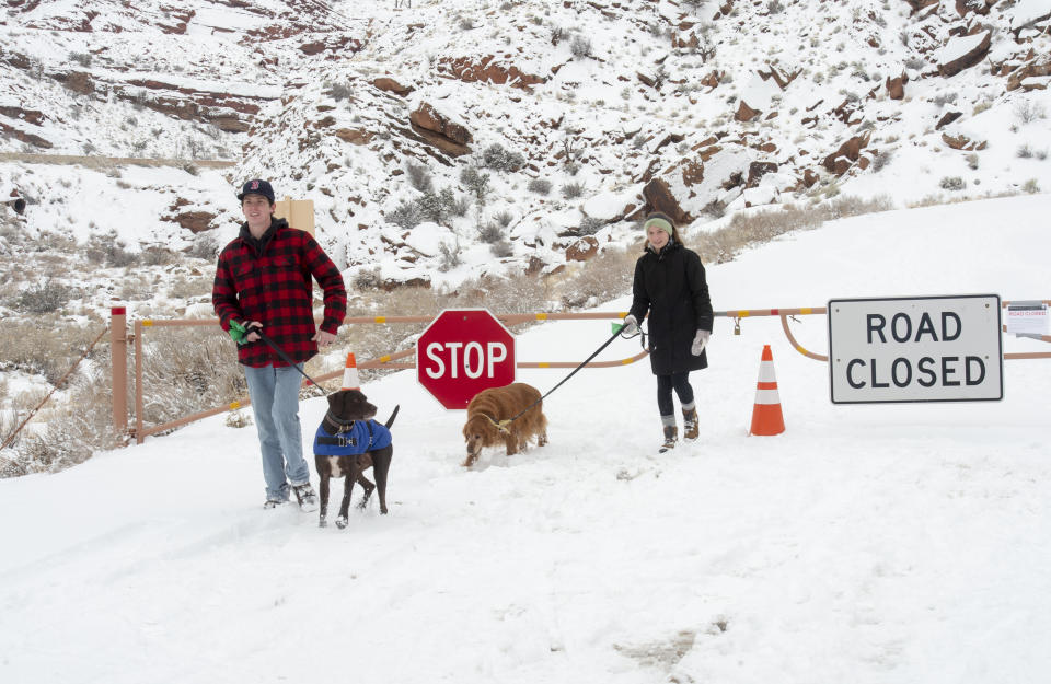 FILE - Parker Smith and Hillary Smith hike along a closed road outside Arches National Park in Utah which is closed due to the partial government shutdown, in January 2019. Arizona's Grand Canyon National Park and all five national parks in Utah will remain open if the U.S. government shuts down, Sunday, Oct. 1, 2023. Arizona Gov. Katie Hobbs and Utah Gov. Spencer Cox say that the parks are important destinations and local communities depend on dollars from visitors. (Rick Egan/The Salt Lake Tribune via AP, File)