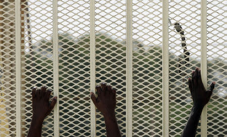 African would-be immigrants hold onto a perimeter fence in an enclosed compound at the Safi detention centre outside Valletta in this July 15, 2008 file photo. REUTERS/Darrin Zammit Lupi/Files