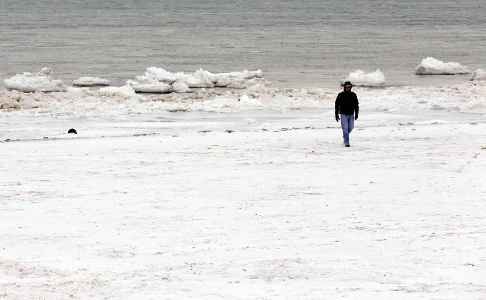 A man walks next to the snow-covered Lake Michigan in Evanston, Ill., Friday, Jan. 3, 2014. The snowstorm may finally have left town but a winter weather advisory is in effect for this evening when southerly winds are expected to kick up blizzard-like conditions. (AP Photo/Nam Y. Huh)