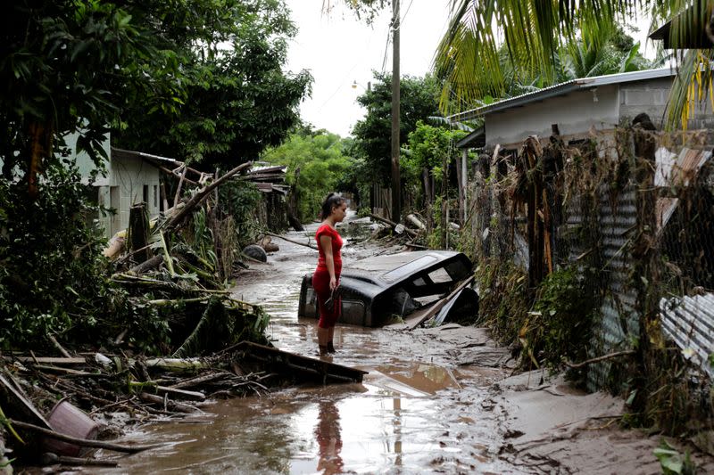 A woman stands outside her home damaged due to heavy rains caused by Hurricane Eta, in Pimienta