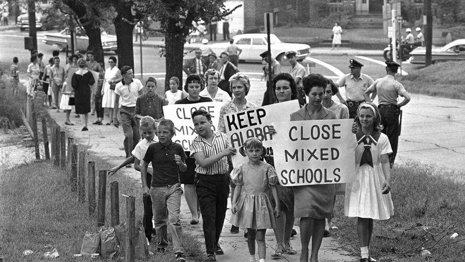 Mothers carrying protest signs accompany their children to Graymont Elementary School in Birmingham, Alabama, which was opened on an integrated basis, in September 1963. - AP