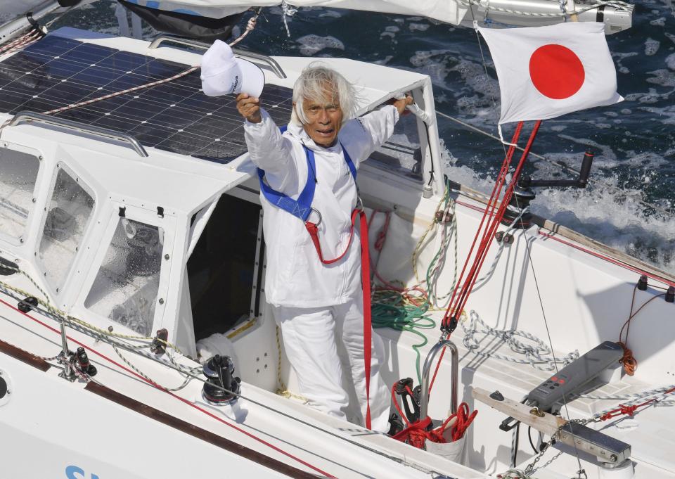 Japan's Kenichi Horie waves on his sailing boat after his trans-Pacific voyage, at Osaka Bay, western Japan, Saturday, June 4, 2022. The 83-year-old Japanese adventurer returned home Saturday after successfully completing his solo, nonstop voyage across the Pacific, becoming the oldest person to reach the milestone.(Kyodo News via AP)