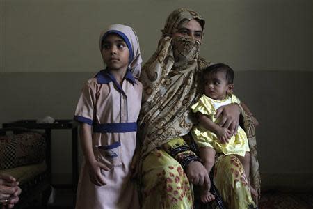 Gul Afroz, wife of Abdul Razzaq Baloch, sits with her daughters Zainab (L) and seven-month-old Sara during an interview with Reuters at her residence in Karachi June 3, 2013. REUTERS/Stringer