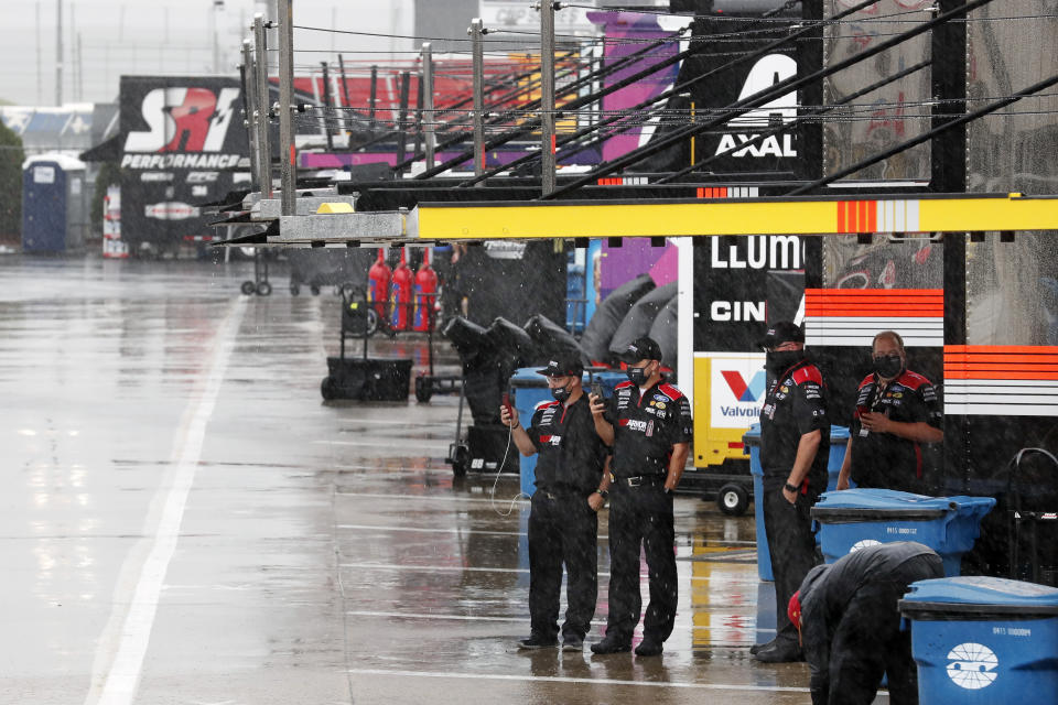 Crew members watch as rain falls before a NASCAR Cup Series auto race at Charlotte Motor Speedway Wednesday, May 27, 2020, in Concord, N.C. (AP Photo/Gerry Broome)