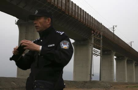 A policeman stands guard under a stretch of the new high-speed rail line between Xinjiang's capital Urumqi and Turpan, June 3, 2014. China showed off its first high-speed rail link to the restive far western region of Xinjiang on Tuesday, promising that it could guarantee the security of an important economic project despite a recent serious escalation in violence. REUTERS/Michael Martina