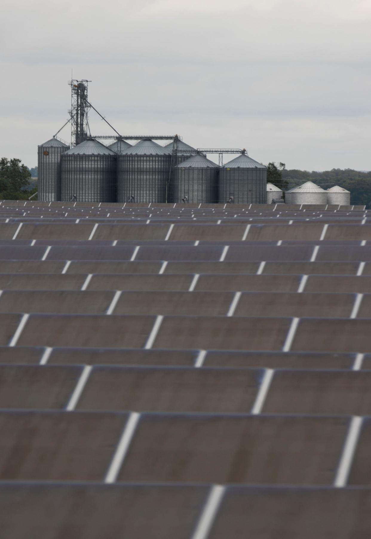 Farm silos appear in the background behind rows of solar panels at the Yellowbud Solar Power Plant on September 28, 2023, in Williamsport, Ohio.