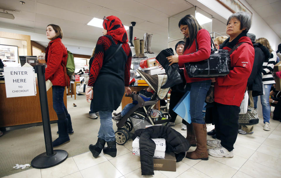 Shoppers wait in the checkout line at Macy's in downtown Boston, Friday, Nov. 23, 2012. Black Friday, the day when retailers traditionally turn a profit for the year, got a jump start this year as many stores opened just as families were finishing up Thanksgiving dinner. (AP Photo/Michael Dwyer)