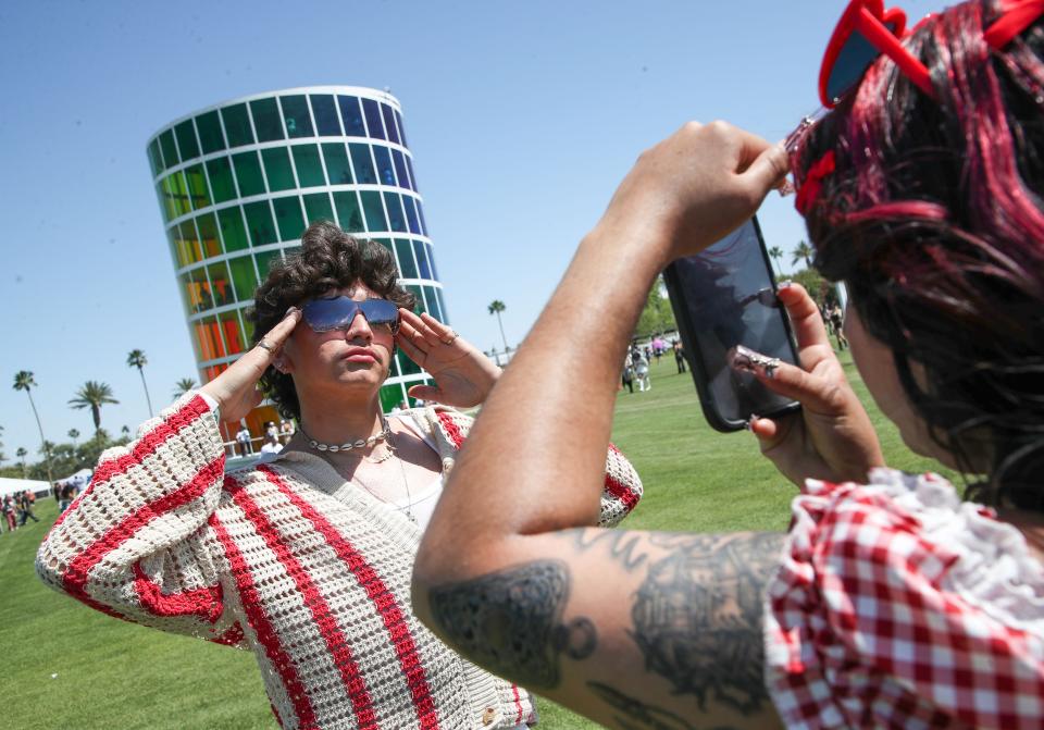 Damian Lira, left, and Ximena Duarte from Torrence, Calif., take photos in front of "Spectra" at the Coachella Valley Music and Arts Festival in Indio, Calif., April 12, 2024.