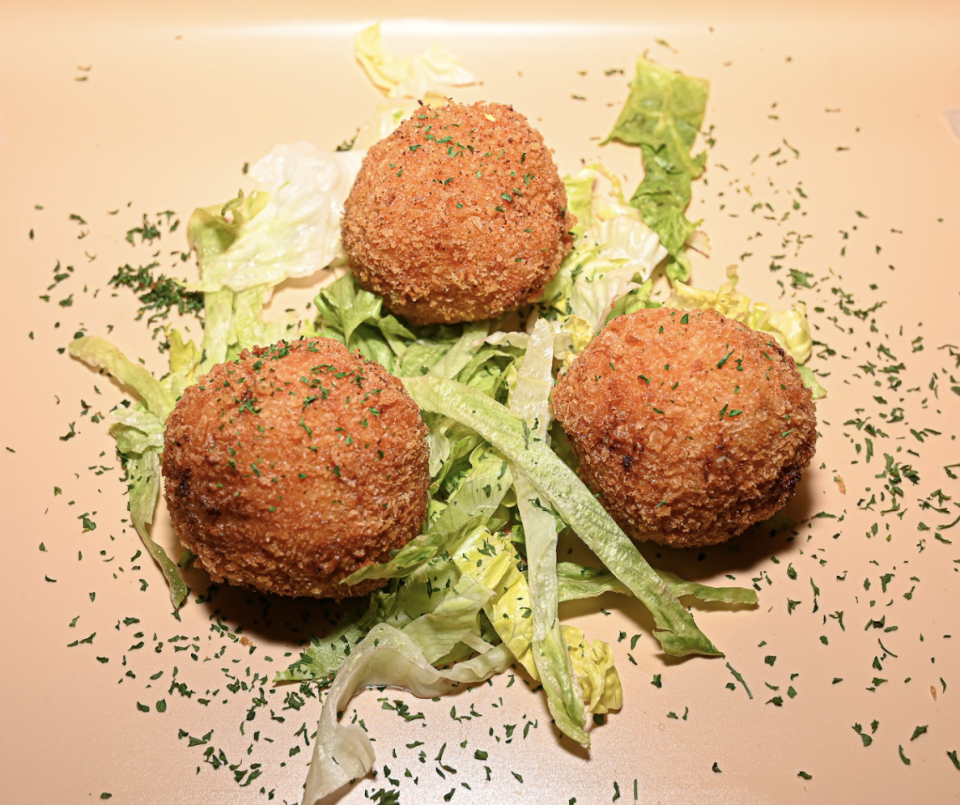 MilTex Kitchen's appetizers include Astroballs, which are deep-fried mac-and-cheese balls atop butter lettuce and drizzled with H-town sauce.