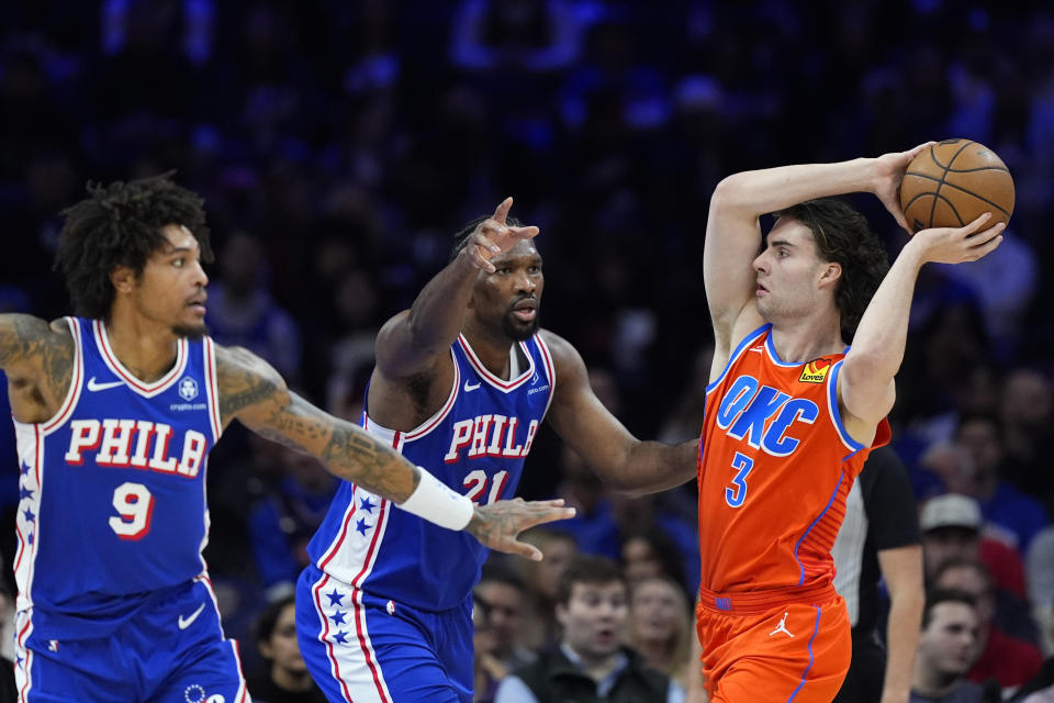 Oklahoma City Thunder's Josh Giddey, right, tries to get past Philadelphia 76ers' Joel Embiid, center, and Kelly Oubre Jr. during the first half of an NBA basketball game, Tuesday, April 2, 2024, in Philadelphia. (AP Photo/Matt Slocum)