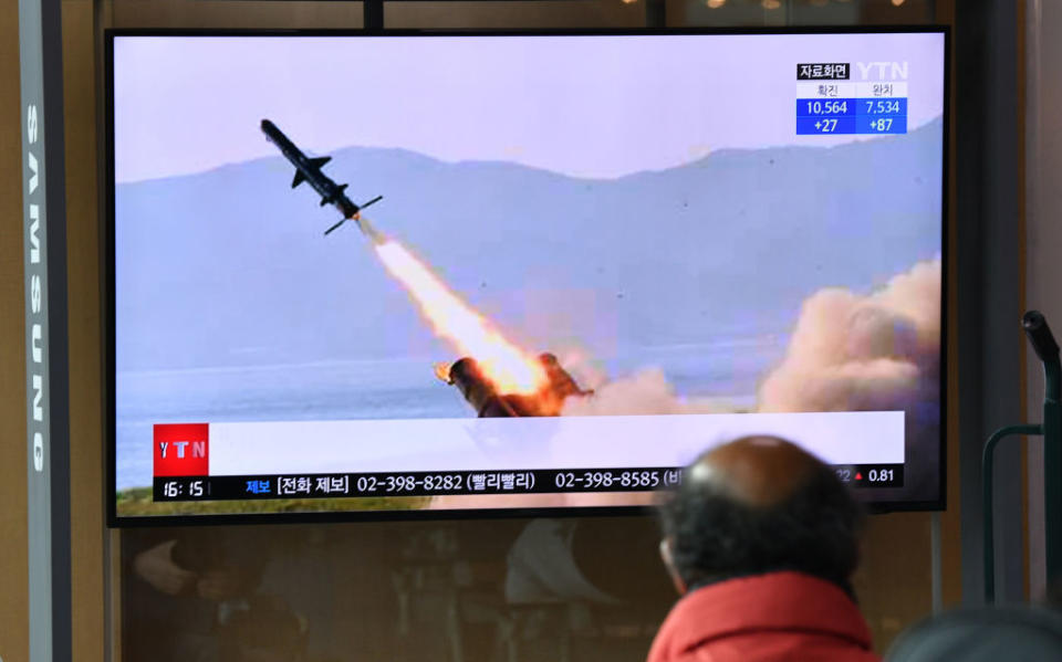 A man watches a television news broadcast showing file footage of a North Korean missile test.
