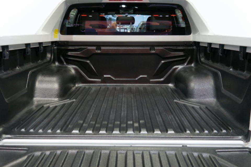 Empty truck bed with ribbed plastic liner and an open tailgate, showcasing the spacious interior of a pickup truck