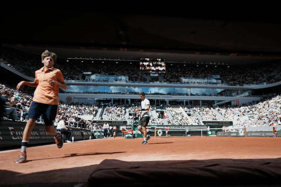 A ball boy runs while Slovenia's Aljaz Bedene plays Serbia's Novak Djokovic during their third round match of the French Open tennis tournament at the Roland Garros stadium Friday, May 27, 2022 in Paris. (AP Photo/Thibault Camus)