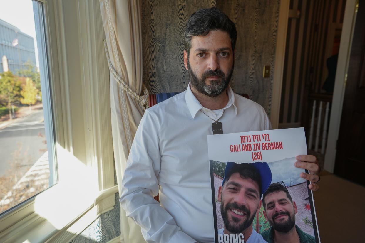 Liran Berman holds a poster of his brothers Gali and Ziv, who were taken hostage during the October 7 attacks by Hamas.