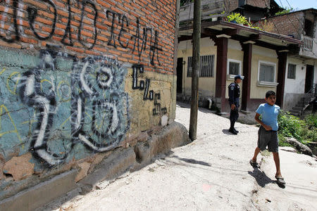 FILE PHOTO: A child walks past a graffiti of the Mara 18 gang at the gang-infested 14 de Marzo neighbourhood in Tegucigalpa May 23, 2014. REUTERS/Jorge Cabrera