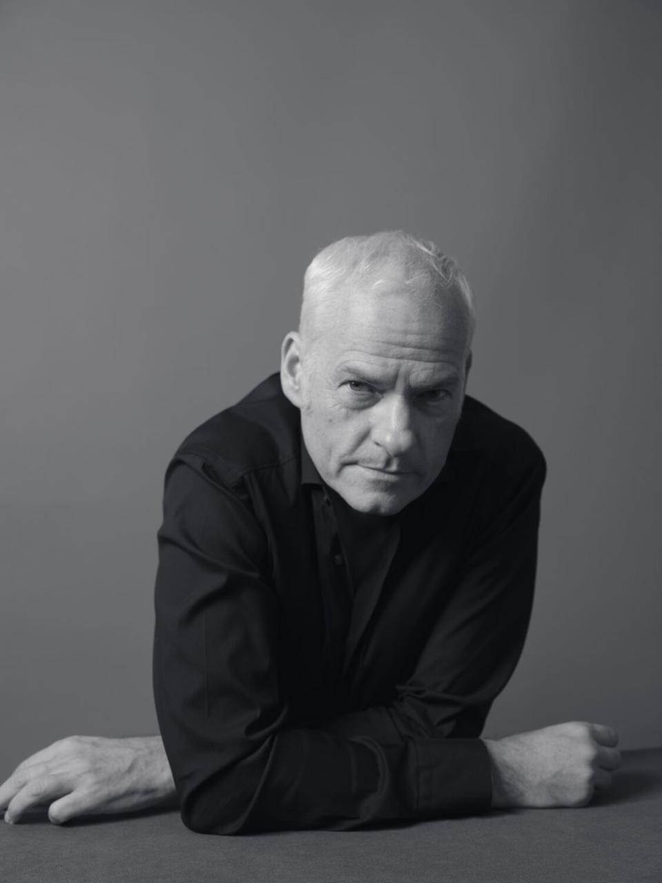 black and white photo of a man leaning against a table