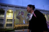 A woman dressed in black passes a poster of Thailand's late King Bhumibol Adulyadej at the Bangkok City Hall Bangkok, Thailand October 14, 2016. REUTERS/Edgar Su