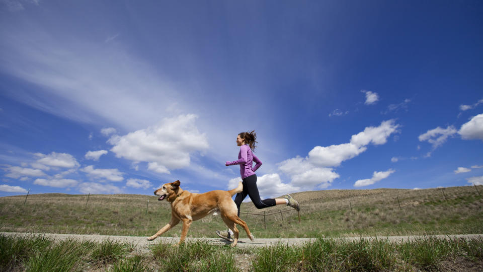 woman running outside with dog