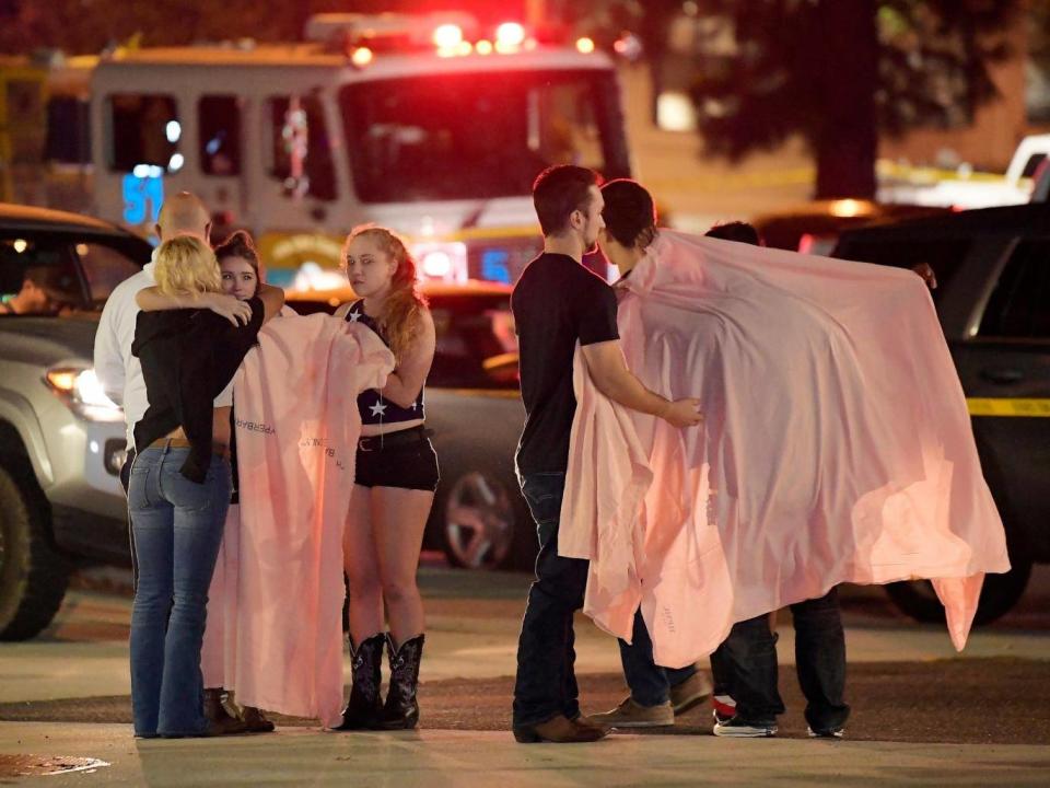 People comfort each other as they stand near the scene 8 November, 2018, in Thousand Oaks, California, where a gunman opened fire inside a country dance bar crowded with hundreds of people on