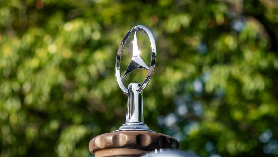 A close-up of the three-pointed-star hood ornament on a classic Mercedes-Benz automobile.